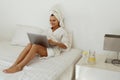 Smiling european girl use laptop while lay on bed