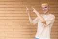 Smiling European man dressed in a beige T-shirt and jeans pointing his fingers to the left at the copy space Royalty Free Stock Photo