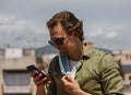 Smiling european man taking off protective mask to unblock the phone. The man is happy to be free and meet with friends.