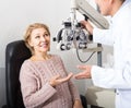 Mature optician examinating eyesight with aid of slit lamp Royalty Free Stock Photo