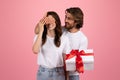 Smiling man surprises a delighted woman by covering her eyes with his hand Royalty Free Stock Photo