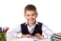 Smiling excellent pupil with exploration magnifier sitting at the table on the white background