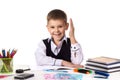 Smiling excellent pupil with hand up sitting at the table on the white background