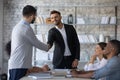 Smiling executive shaking successful employee hand at corporate meeting