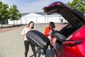 Young girls put their bags in open trunk of car Royalty Free Stock Photo