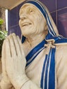 Smiling face with folded hands statue of mother Teresa with blue background