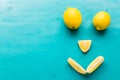 Smiling face made from half of ripe yellow fruit on blue background top view with copy space, happy diet, lemons and