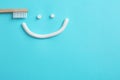 Smiling face made of toothpaste, brush on color background, top view