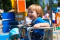 Smiling fair child boy riding amusement ride