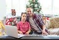 Smiling family on Christmas morning play music on piano.