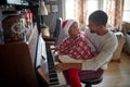 Family on Christmas morning play music on piano