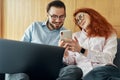 Smiling family couple laughing using computer and smartphone Royalty Free Stock Photo