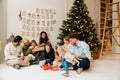 Smiling family exchanging and opening gifts while sitting near Christmas tree Royalty Free Stock Photo