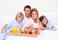 Smiling family having breakfast sitting on bed Royalty Free Stock Photo