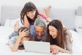 Smiling family lying on bed using their laptop Royalty Free Stock Photo