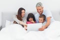 Smiling family lying in bed using their laptop Royalty Free Stock Photo