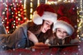 Smiling family mother and daughter in santas hats and pajamas watching funny video or choosing gifts on digital tablet Royalty Free Stock Photo