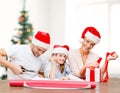 Smiling family in santa helper hats with gift box Royalty Free Stock Photo