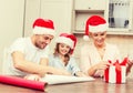 Smiling family in santa helper hats with gift box Royalty Free Stock Photo