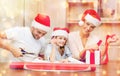 Smiling family in santa helper hats with gift box Royalty Free Stock Photo