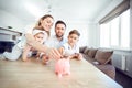 A smiling family saves money with a piggy bank. Royalty Free Stock Photo