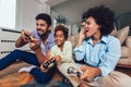Family sitting on the couch together playing video games, selective focus Royalty Free Stock Photo