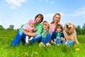 Smiling family sitting on green grass with dog