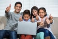 Smiling family on the sofa showing their thumbs up Royalty Free Stock Photo