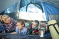 Smiling family talking while lying in the tent
