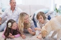 Smiling family with their pet yellow labrador on the rug Royalty Free Stock Photo