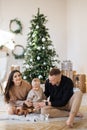 Smiling family trio celebrating holidays near Christmas tree Royalty Free Stock Photo