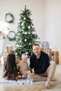 Smiling family trio celebrating holidays near Christmas tree Royalty Free Stock Photo