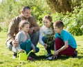 Smiling family with two kids placing a new tree