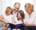 Smiling family and two little girls with book Royalty Free Stock Photo