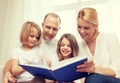 Smiling family and two little girls with book Royalty Free Stock Photo