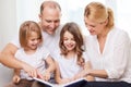 Smiling family and two little girls with book Royalty Free Stock Photo