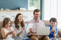 Smiling family using digital tablet, phone and laptop in living room Royalty Free Stock Photo