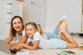 Smiling family using laptop computer together lying on floor in children room with modern light interior, looking at Royalty Free Stock Photo