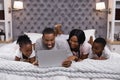 Smiling family using laptop while lying together on bed Royalty Free Stock Photo