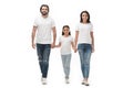 smiling family in white shirts and jeans holding hands while walking together