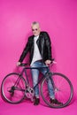 Smiling fashionable senior man wearing leather jacket and sunglesses standing with bicycle