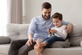 Smiling father and cute little son using phone apps together Royalty Free Stock Photo