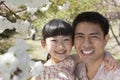 Smiling father and daughter enjoying the cherry blossoms on the tree in the park in springtime, portrait Royalty Free Stock Photo