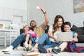 smiling father and daughter taking selfie on smartphone while mother and son using laptop together Royalty Free Stock Photo