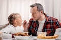 smiling father feeding adorable little girl