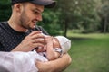 Smiling father feeding his baby boy outside with a bottle Royalty Free Stock Photo