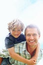 Smiling father giving his son piggy back ride against sky. Portrait of a smiling father giving his son piggy back ride Royalty Free Stock Photo