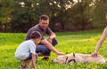 Father and his son playing with dog in park -happy family is having fun with golden retriever . Royalty Free Stock Photo