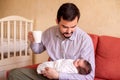 Smiling young father having a break: holding infant baby daughter in one arm and mug of coffee or tea in another hand. Royalty Free Stock Photo