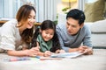 Smiling Father, Mother and daughter drawing together on paper at home Royalty Free Stock Photo
